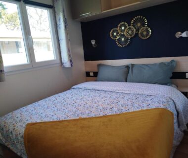 Chambre double avec lit fenêtre et décoration murale dans le mobil home cosy