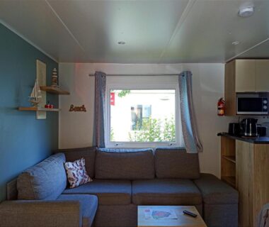 Intérieur avec canapé et kitchenette du mobil home dans Camping 4 étoiles