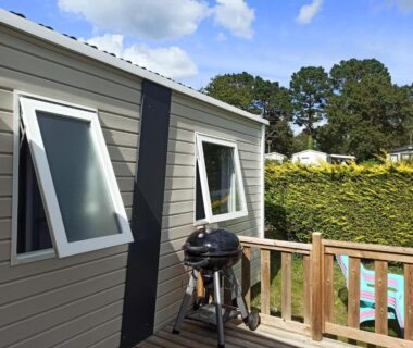Terrasse avec barbecue et vue sur la piscine du Mobil home dans Camping 4 étoiles
