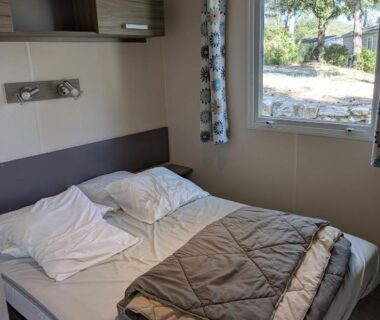 Chambre avec lit double et fenêtre sur arbres au Mobil-home dans les Gorges du Verdon