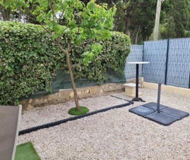 Espace extérieur en gravier avec un arbre et socles de mobilier du Mobil home de Patricia et Franck à Sigean