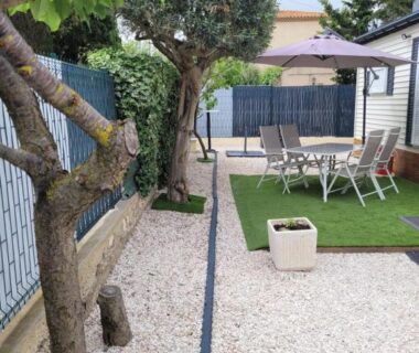Terrasse avec salon de jardin parasol et pelouse du Mobil home de Patricia et Franck à Sigean