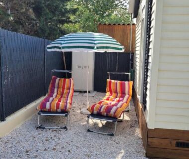 Espace extérieur gravillonné avec deux transats et parasol du mobil home de Patricia et Franck à Sigean