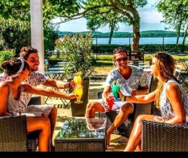 Terrasse au bord du lac avec quatre personnes autour d'une table au Mobil-home du Lac Mimizan