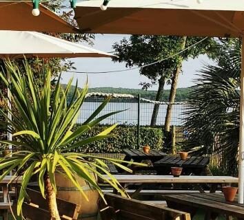 Terrasse au bord du lac avec tables bancs et parasols du Mobil-home du Lac Mimizan