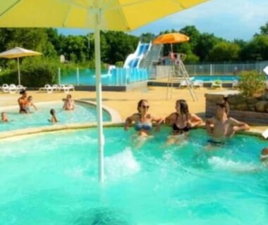 Piscine extérieure avec toboggan et parasol au Mobil-home du Lac Mimizan