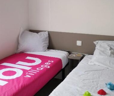 Chambre avec deux lits simples et linge de lit contrasté dans le Mobil home famille Calazel