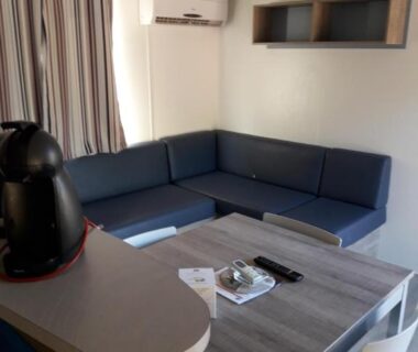 Intérieur salon avec canapé d'angle et table dans le mobil home Florida au camping Les Cigales