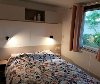 Chambre avec lit et fenêtre dans le mobil-home haut standing Séjour idéal entre Lac et Océan