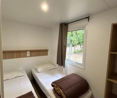 Chambre avec deux lits et fenêtre sur jardin du Mobil home ile de loisirs de buthiers