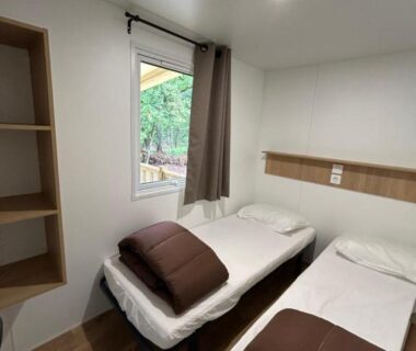 Chambre avec deux lits et fenêtre dans le mobil home ile de loisirs de buthiers