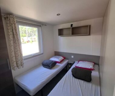 Chambre avec deux lits simples et fenêtre dans le Mobil home les Embruns