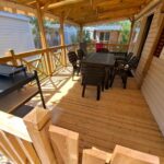 Terrasse couverte en bois avec table chaises et barbecue du mobil home les Embruns