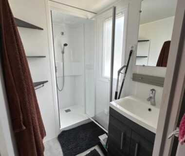 Salle de bain avec douche cabine lavabo miroir et serviettes dans le mobil home les Embruns