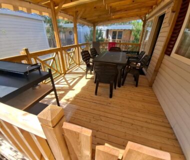 Terrasse couverte en bois avec table chaises et barbecue du mobil home les Embruns