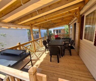 Terrasse couverte en bois avec table et barbecue du mobil home les Embruns