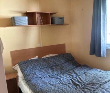 Chambre avec lit double et étagère murale dans le Mobil home les sables d or
