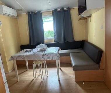 Intérieur coin repas avec banquette table et fenêtre dans le mobil home les sables d or