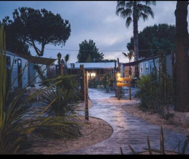 Allée en bois bordée de végétation et mobil homes au crépuscule au Mobil home les sables d'or