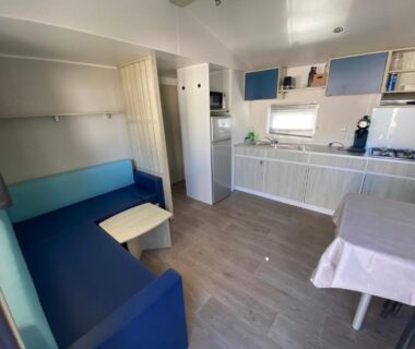Coin salon avec canapé bleu kitchenette et table du mobil-home narbonne plage