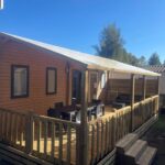 Terrasse en bois avec table et chaises du mobil-home neuf 6 à 8 pers au Camping Les Palmiers