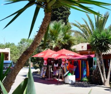 Allée de boutiques et parasols rouges au Camping Les Palmiers