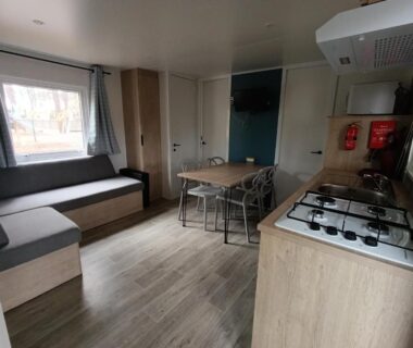 Intérieur avec coin cuisine et banquette du mobil-home neuf sous les pins