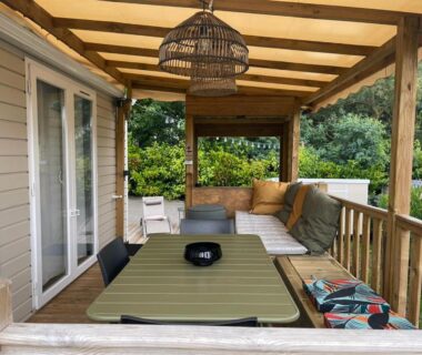 Terrasse couverte avec table et salon extérieur du mobil home au Cap Ferret Camping les viviers