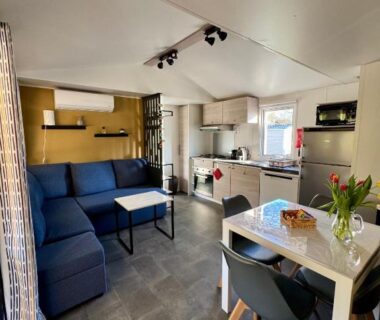 Intérieur avec canapé coin repas et cuisine du mobil-home plage à pied Camping 4 étoiles