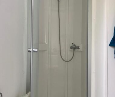 Cabine de douche avec pommeau et porte vitrée dans le Mobil home près de l étang
