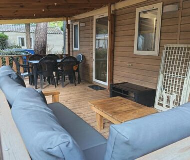 Terrasse couverte avec canapés et table à manger du Mobil home prestations DELUXE 3ch climatisé avec Parc Aquatique