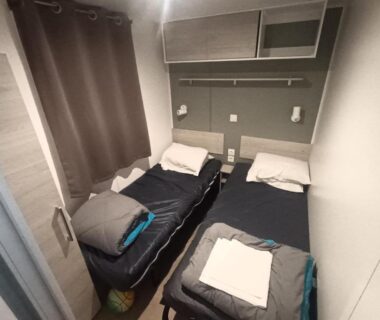 Chambre avec deux lits et rangements du Mobil home prestations DELUXE 3ch climatisé avec Parc Aquatique