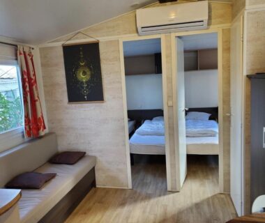 Intérieur du mobil home avec salon, chambre et climatisation dans Mobil home récent clim 3ch Camping3* piscine