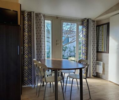 Séjour avec table et chaises et baie vitrée dans le Mobil home récent clim 3ch Camping3* piscine