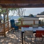 Terrasse en bois avec table et chaises et vue mer du mobil-home récent 2025 au Camping Domaine l'Île d'Or
