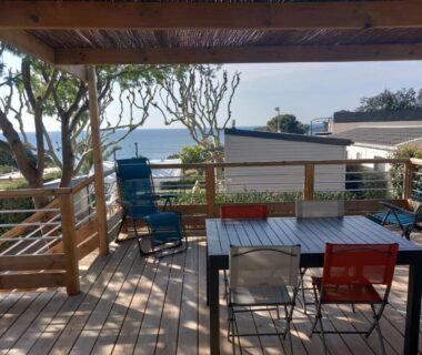 Terrasse en bois avec table et chaises et vue mer du mobil-home récent 2025 au Camping Domaine l'Île d'Or