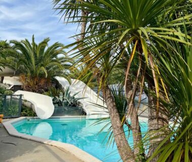 Piscine extérieure avec toboggan et palmiers au mobil home spacieux 5 personnes à 15 min de Concarneau