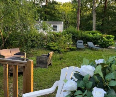 Terrasse en bois avec fauteuils et jardin du Mobil home tout confort