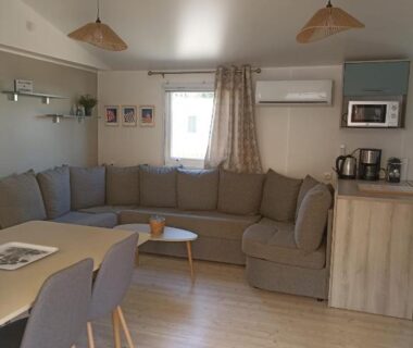 Séjour avec canapé et kitchenette du mobil home tout confort 6 personnes
