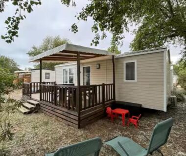 Terrasse en bois avec chaises et coin extérieur sous les arbres du Mobil home tout confort Camping la falaise