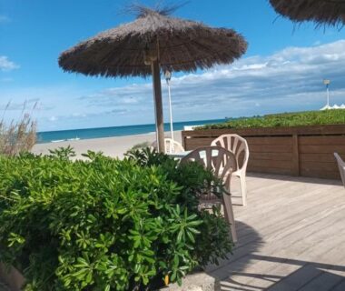 Terrasse en bois avec parasol et chaises face à la plage du Mobil home tout confort canet plage
