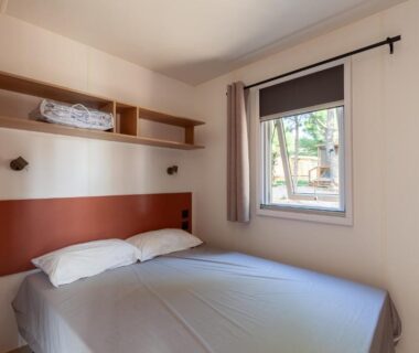 Chambre avec lit double et fenêtre donnant sur l'extérieur dans le Mobil home tout équipé