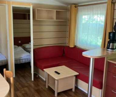 Intérieur du mobil home avec canapé kitchenette et lits superposés au Camping de Bairon Mobil homes 6 et 8 places