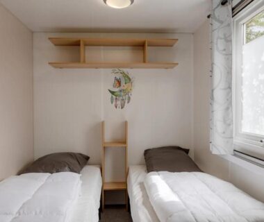 Chambre avec deux lits simples et fenêtre dans les Mobil-homes proche de l’océan