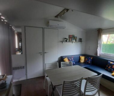 Intérieur salon avec table et banquette dans le MobilHome de Charlotte au Camping La Falaise 4 étoiles