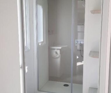Salle de bain avec douche et sol stratifié dans le MobilHome de Charlotte au Camping La Falaise 4 étoiles