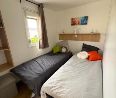 Chambre avec deux lits et fenêtre dans le MobilHome de la Coccinelle