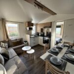 Intérieur avec canapé et cuisine ouverte dans le Mobile Home 168 du Camping Siblu Lac des Rêves Perols