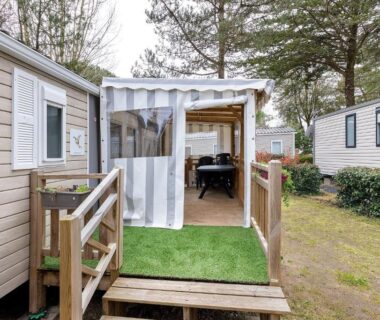 Terrasse couverte avec tapis gazon et escalier au Mobile Home 44 Bois Dormant