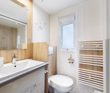 Salle de bain avec lavabo miroir WC et sèche-serviettes dans le Mobile Home 44 Bois Dormant